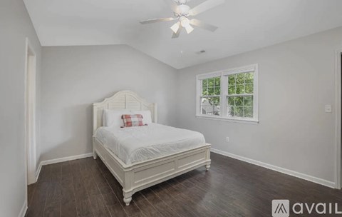 A bedroom with a large bed and a ceiling fan.