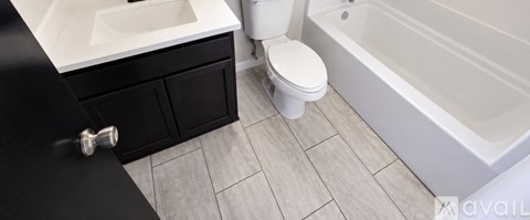 A white toilet sits next to a white sink in a black cabinet.