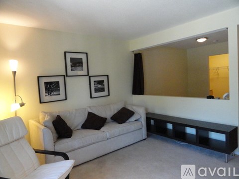 A living room with a white couch and a lamp.