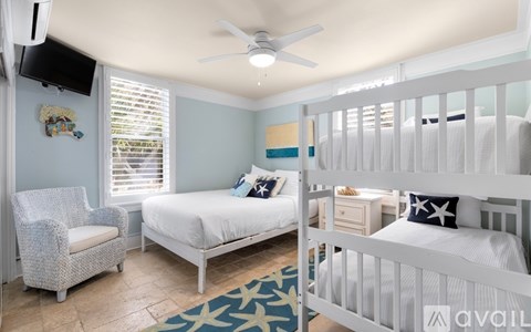 A bedroom with a white bed and a white chair.