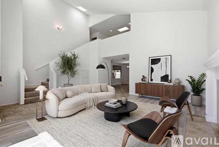 A living room with a white couch and a wooden chair.