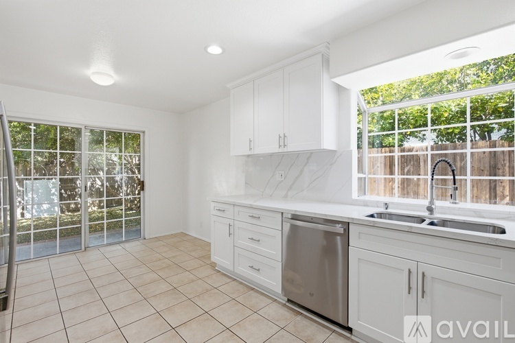 A kitchen with white cabinets and a stainless steel dishwasher and sink.