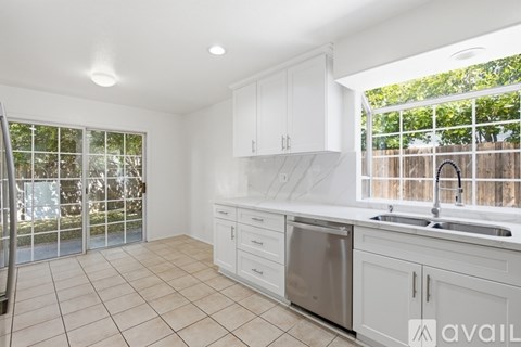 A kitchen with white cabinets and a stainless steel dishwasher and sink.