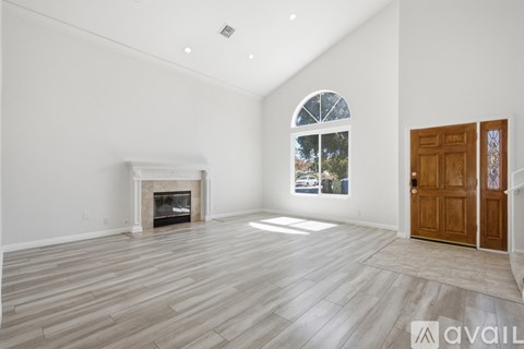A spacious room with a fireplace and a large window.