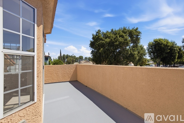 A balcony with a view of trees and a clear sky.
