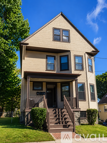 A two-story house with a front porch and a tree to the left.