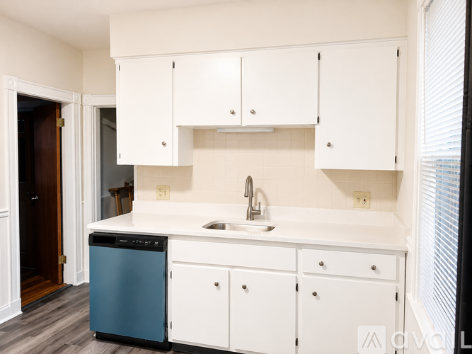 A kitchen with white cabinets and a blue dishwasher.