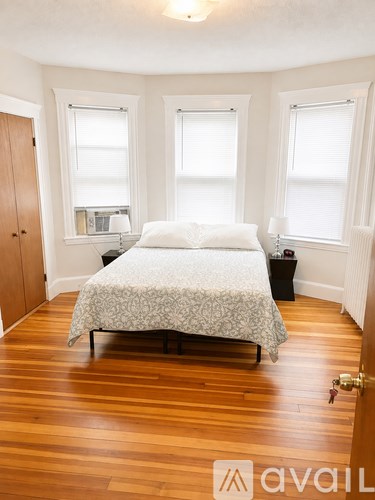 A bedroom with a bed, nightstands, and a window.