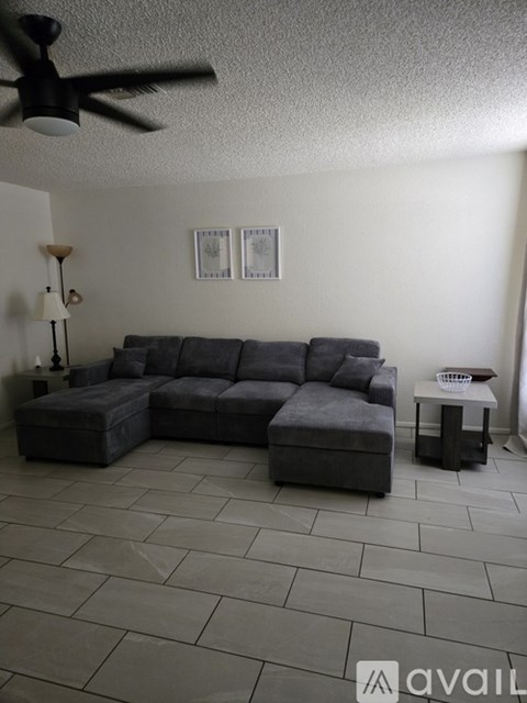 A living room with a grey sofa and a fan on the ceiling.