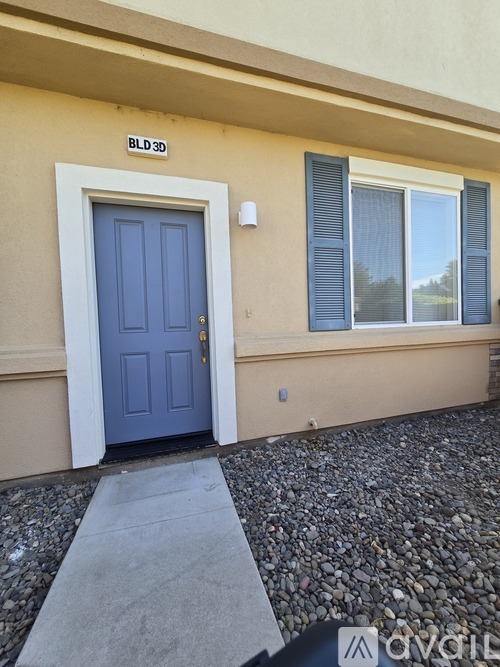 A blue door is on the left side of a tan building.