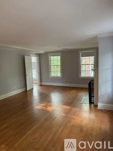 A room with wooden floors and a window with a view of trees.