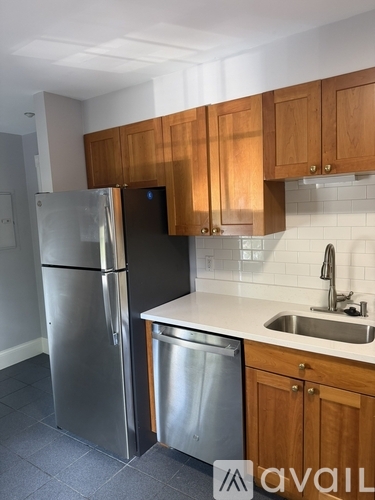 A kitchen with wooden cabinets and a stainless steel refrigerator.