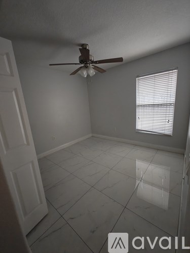 A room with a ceiling fan and a window with blinds.