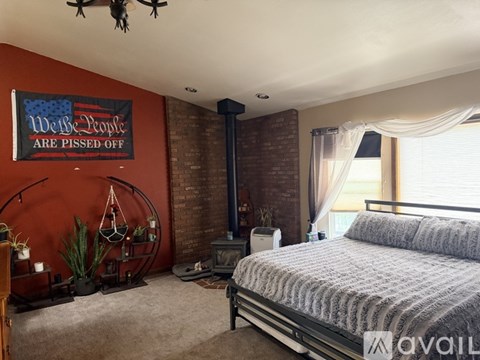 A bedroom with a bed, a ceiling fan, and a wall hanging that says "We the People are pissed off.".