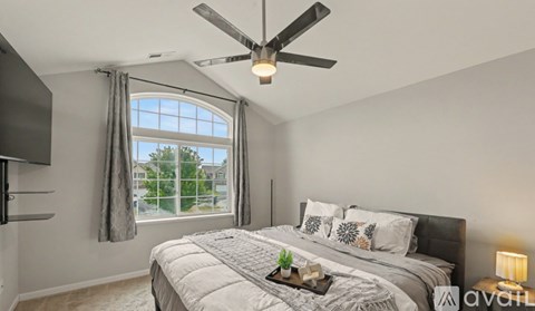 A bedroom with a large bed and a ceiling fan.