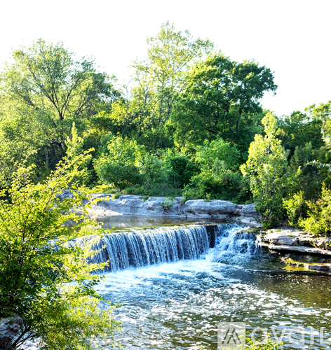 A small waterfall surrounded by green trees.