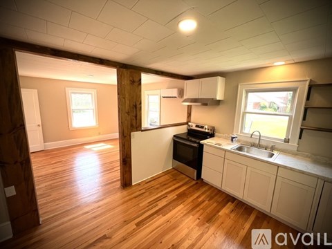 A kitchen with wooden floors and white cabinets.