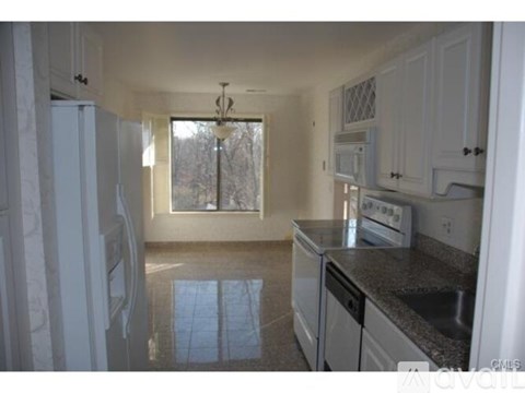 A kitchen with white cabinets and a window.