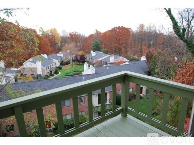 A balcony overlooks a residential area with houses and trees.