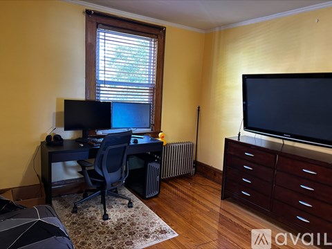A room with a desk, computer, and television.