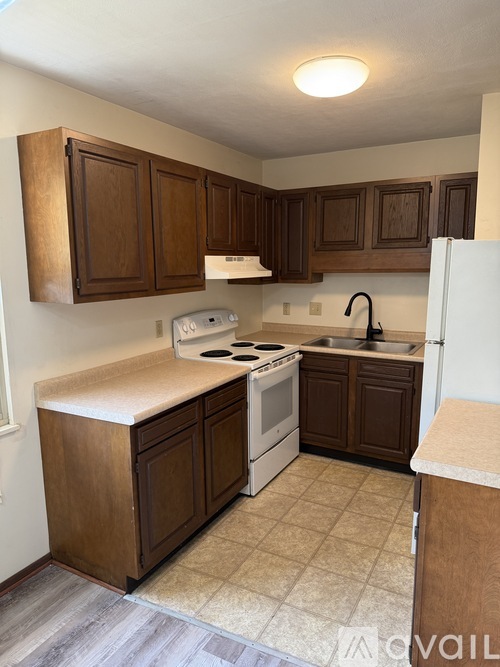 A kitchen with brown cabinets and a white stove top oven.