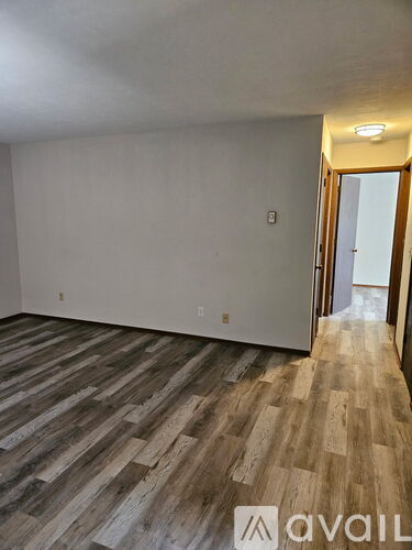 A room with wooden flooring and a doorway leading to another room.