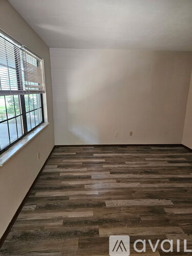 A room with wooden flooring and a window with blinds.