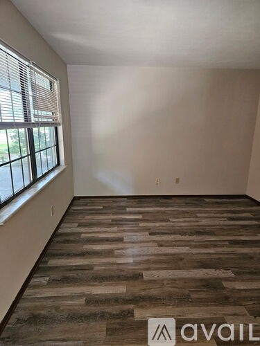 A room with wooden flooring and a window with blinds.