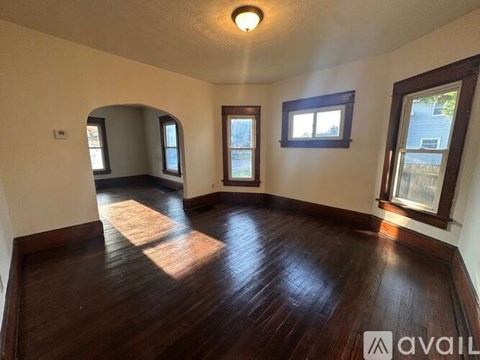 A room with wooden floors and three windows.