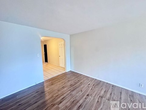 A room with a wooden floor and a doorway leading to another room.