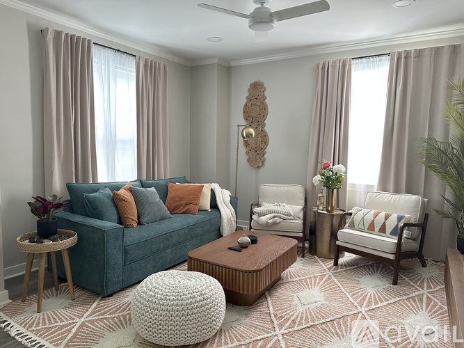 A living room with a blue couch, a white chair, and a wooden coffee table.