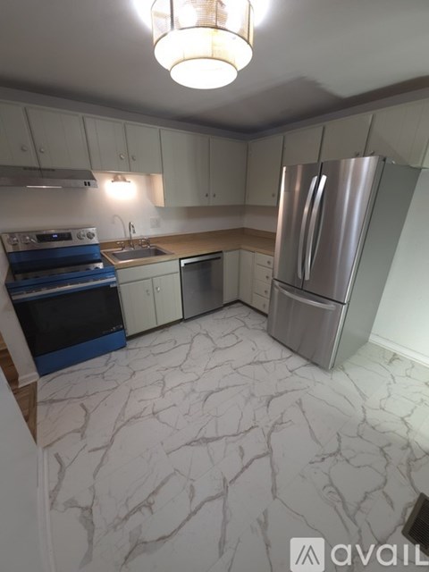 A kitchen with marble flooring and stainless steel appliances.