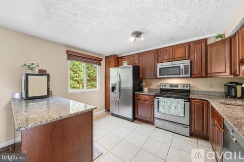 A kitchen with a refrigerator, microwave, oven, and a counter with a plant on it.