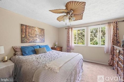 A bedroom with a large bed and a ceiling fan.