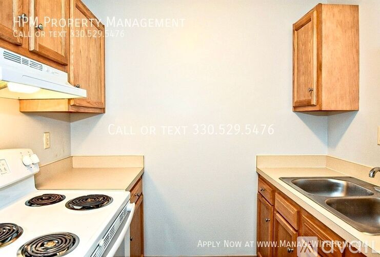 A kitchen with a stove, sink, and cabinets with a sign on the wall.