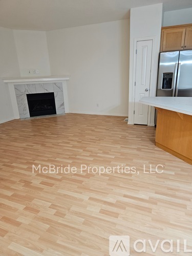 A room with a fireplace and a kitchen area with a refrigerator.