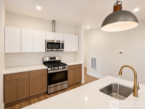 A modern kitchen with a stainless steel oven and microwave, wooden cabinets, and a white countertop.