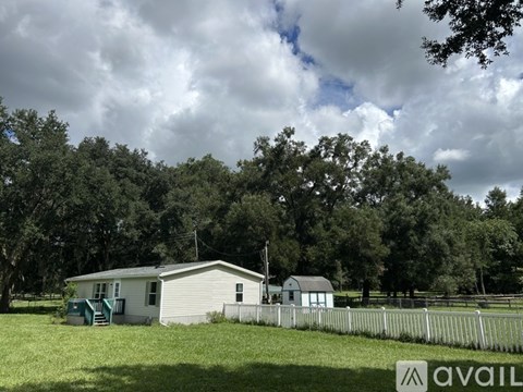A house with a fence and trees in the background.