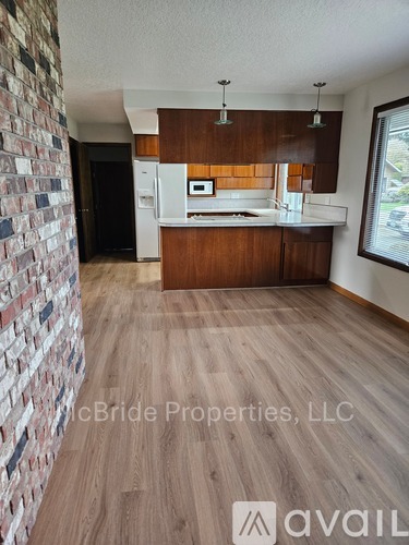 A kitchen with a brick wall and wooden floors.