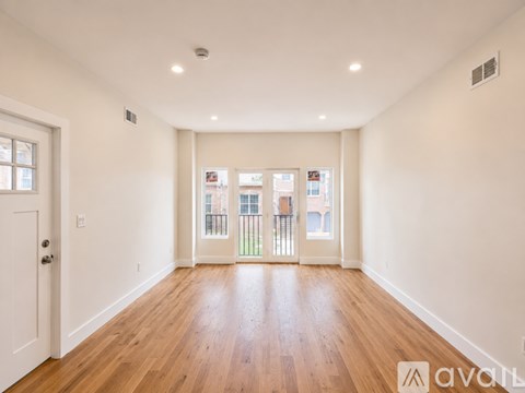 A spacious room with wooden floors and white walls.