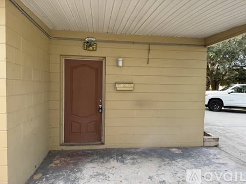 A brown door is on the left side of a tan wall.