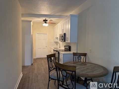 A kitchen with a table and chairs in the foreground and a doorway leading to another room in the background.