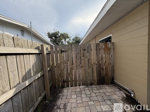 A wooden fence and a brick pathway in front of a house.