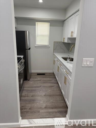 A kitchen with white cabinets and a black fridge.