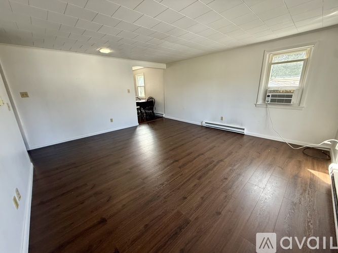 A spacious room with wooden flooring and a window.