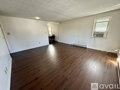 A spacious room with wooden flooring and a window.