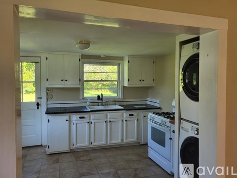 A kitchen with white cabinets and a black countertop.