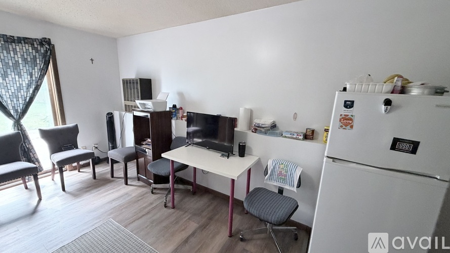 A kitchen area with a refrigerator, a table with chairs, and a television.