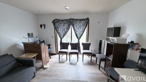 A living room with a grey sofa, a wooden table, and a black curtain.