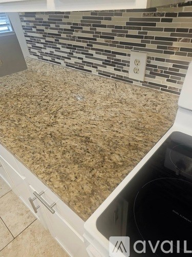 A kitchen counter with a granite countertop and a tiled backsplash.